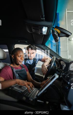 Mechanics using laptop for car diagnostics in auto repair shop Stock Photo