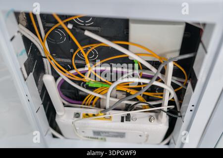 Fiber optic cables connected to internet router in wall box Stock Photo