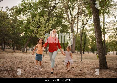 Mother and daughters walking in the park holding hands Stock Photo