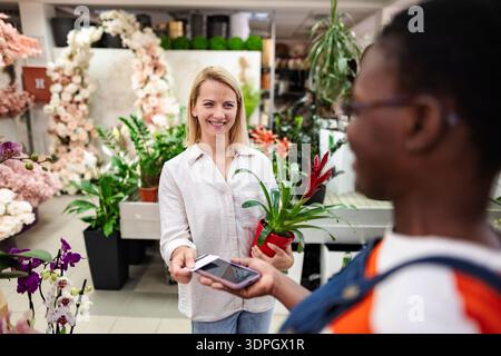 Woman paying with smartphone in a flower shop Stock Photo