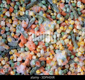 Frozen mixed vegetables are spread out on a clean kitchen surface. The mix contains peas, carrots, corn, and green beans. It looks fresh and ready to Stock Photo