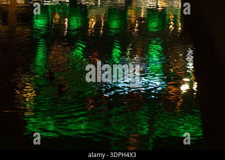 Nighttime city scene in Amsterdam showing colorful reflections of urban lights on a river creating a beautiful glowing abstract and atmospheric background with water ripples and vibrant hues Stock Photo