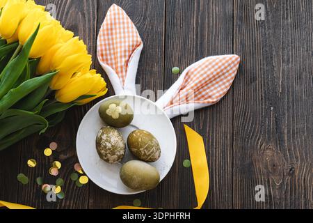Easter flat lay composition with yellow tulips, natural dyed Easter eggs Stock Photo