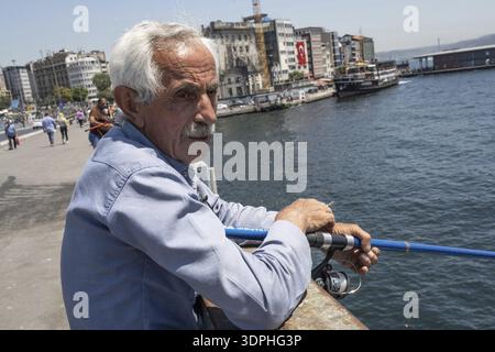 Istanbul, Turkey. June 23rd 2025. An old Turkish man fishing on the Galata Bridge near Karikoy ferry port on the European side of Istanbul, Turkey Stock Photo