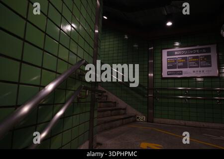 Dimly lit subway or building entrance with green tiled walls and metal handrails in Komazawa, Tokyo Stock Photo