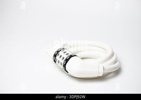 Close-up white flexible coiled cable bike lock with 4-digit combination dial on white. Stock Photo