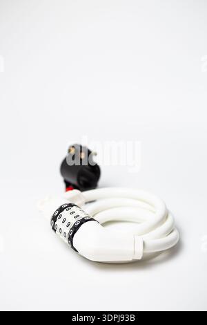 White combination coiled cable lock with mounting bracket for bicycle frame on white background. Stock Photo