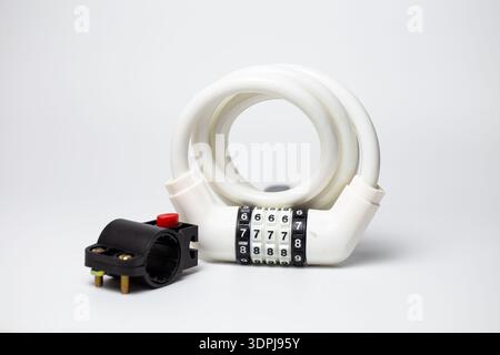 White combination coiled cable lock with mounting bracket for bicycle frame on white background. Stock Photo