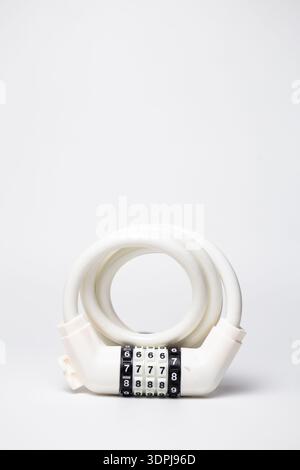 White coiled combination cable lock for bike and scooter security on white background. Stock Photo