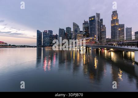 Sinpapore: The lights of the skyscrapers of Singapore business district reflect on the water of the Marina bay in Singapore during sunset. Stock Photo