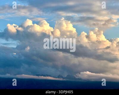 Towering cumulus clouds glowing in warm yellow evening sunlight, creating a dramatic and atmospheric sky scene. Stock Photo