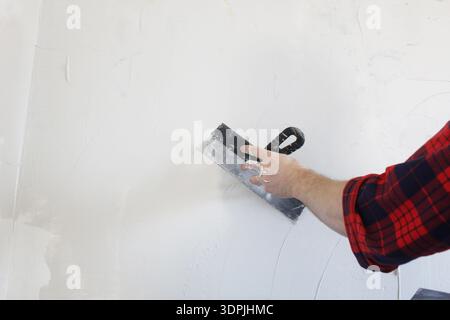 Master puttying wall with spatula close-up. Stock Photo