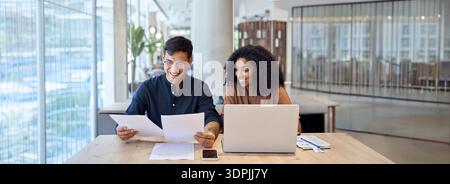 Business man and woman talking using laptop checking documents in office. Stock Photo