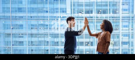 Happy diverse business team man and woman giving high five at work in office. Stock Photo