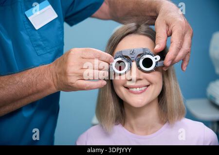 Happy woman having special construction on while trying on different lenses Stock Photo