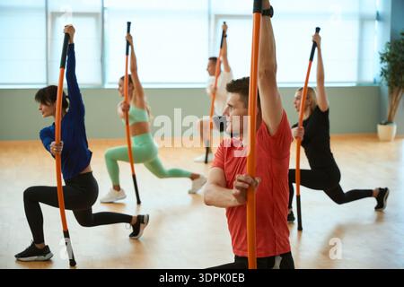 Sporty people doing exercises with gymnastic sticks in gym Stock Photo