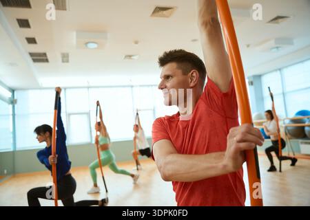 Sporty man doing exercises with gymnastic sticks in gym Stock Photo