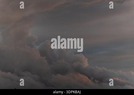 Clouds are forming in sky. It's late in day. Clouds are dense and gray. Sky shows different shades. Stock Photo