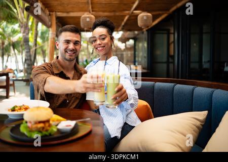 Young couple sharing dining experience at tropical restaurant, engaging with their online followers Stock Photo