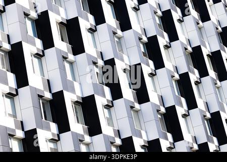 The exterior of a contemporary building showcases a bold, repeating pattern of alternating black and white panels with recessed windows Stock Photo