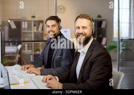 Smiling call center operators at desktops providing customer service support Stock Photo