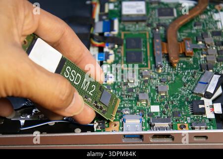 The technician is installing an M.2 hard drive. Stock Photo