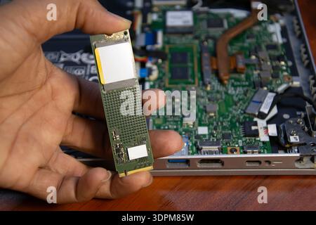 The technician is holding an M.2 hard drive. Stock Photo
