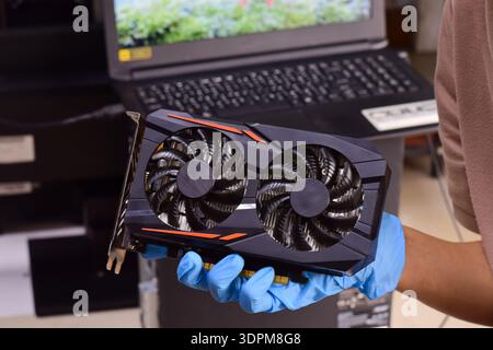 The technician is holding a computer graphics card and other computer components. Stock Photo