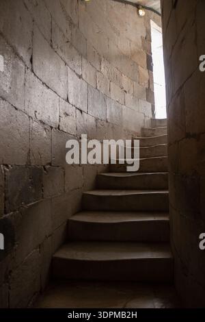 Interior view of the spiral stone staircase inside the Leaning Tower of Pisa, Italy. Natural light enters from above, illuminating the curved medieval Stock Photo