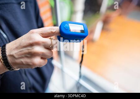 Woman resting at home using pulse oximeter to monitor blood oxygen levels and pulse rate. Stock Photo