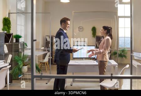 Businessman and businesswoman discussing strategy with tablet in modern glass office Stock Photo