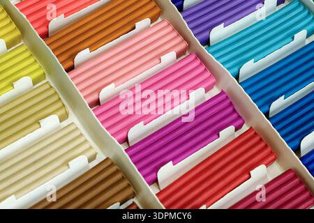 Pieces of multi-colored plasticine neatly arranged in a simple cardboard box. Close-up shot, abstract background for themes related to art supplies, c Stock Photo