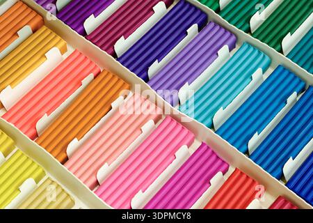 Pieces of multi-colored plasticine neatly arranged in a simple cardboard box. Close-up shot, abstract background for themes related to art supplies, c Stock Photo