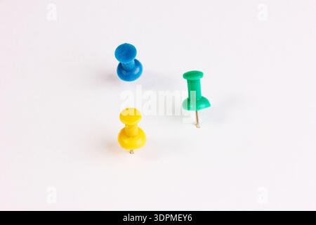 A triple set of real plastic pins in different colors, isolated on a white background with real shadows. The pins are shown in different orientations. Stock Photo