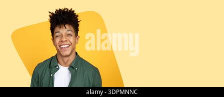 Smiling Young Man in a Green Shirt Against a Yellow Background Looking Cheerful and Friendly Stock Photo