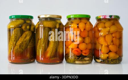 Glass jars with salted pickled tomato and cucumbers in tomato sauce, homemade preservation on a light background. Natural ingredients highlight fresh, Stock Photo