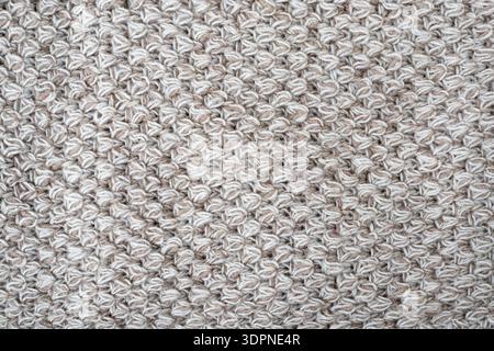 Wool gray crochet blanket as background. Knitted macro texture, close-up of beige crocheted front surface, woolen texture of woolen wool, knitted fron Stock Photo