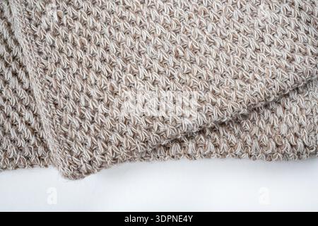 Folded knitted beige woolen blanket. Beige knitted blanket on white background with copy space template. Flat lay, top view Stock Photo