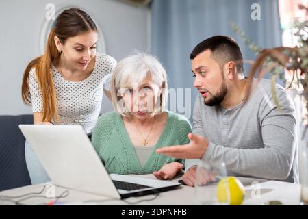 Portrait of an elderly mother and adult children at the table together with laptop Stock Photo