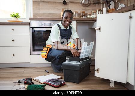 Female plumber searching tools in toolbox in kitchen sink cabinet Stock Photo
