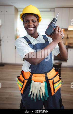 African american female construction worker holding cordless drill smiling at camera Stock Photo