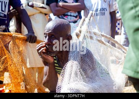 Argungu, Nigeria - 14 February 2026: View of an elder with weathered skin and a thoughtful gaze, holding a fishing net amidst the vibrant energy at th Stock Photo