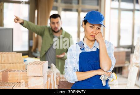 Frustrated female contractor in building under renovation with displeased customer Stock Photo