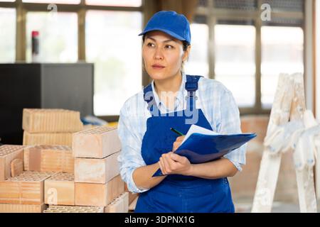 Woman making notes on indoor construction site Stock Photo