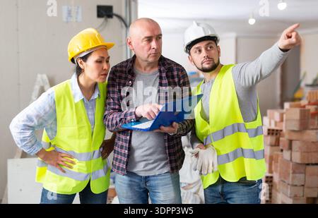 Homeowner with laptop discussing home renovation with builders Stock Photo