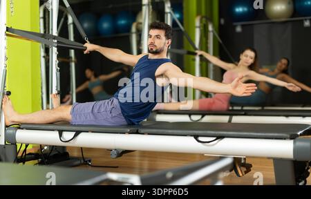 Young man doing abdominal press exercise on pilates reformer Stock Photo