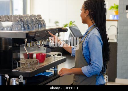 Commercial espresso machine preparing espresso shots into red mugs on countertop in coffee shop Stock Photo
