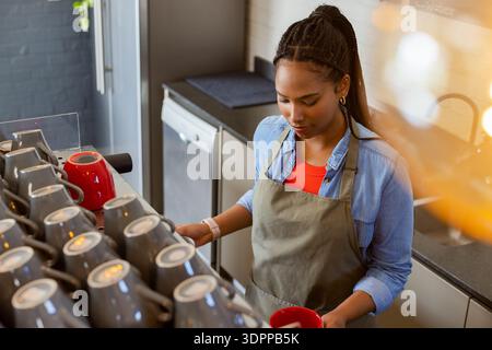 African American female barista in apron pulling shot on espresso machine at cafe, copy space Stock Photo