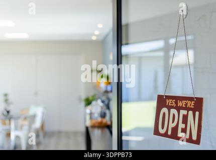 Red and beige sign is hanging on glass door, revealing blurred cafe chairs and counter Stock Photo