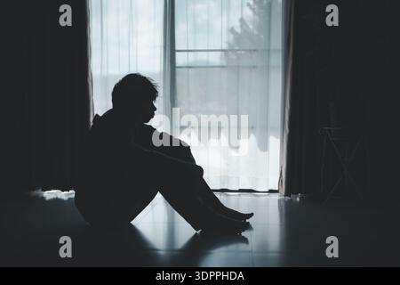 Silhouette of lost cast long shadow, embodying deep despair and hopelessness left him feeling perpetually stressed, sad, and unhappy. man sat alone, f Stock Photo